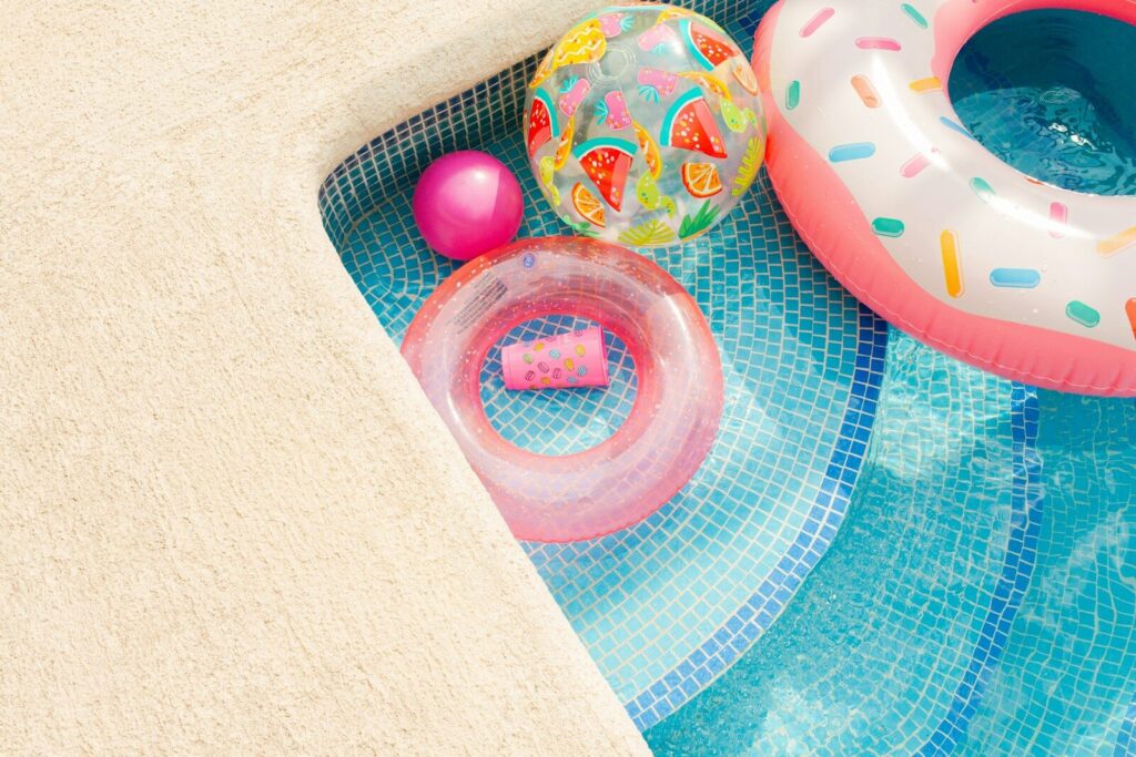 Inflatable pool toys floating in a blue swimming pool.